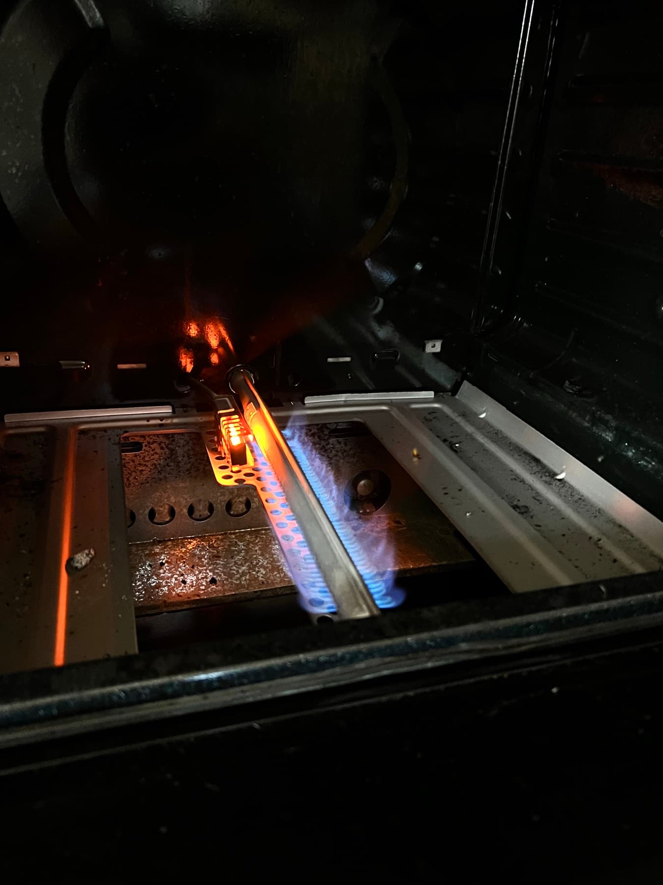 Technician testing an oven igniter inside an open oven cavity