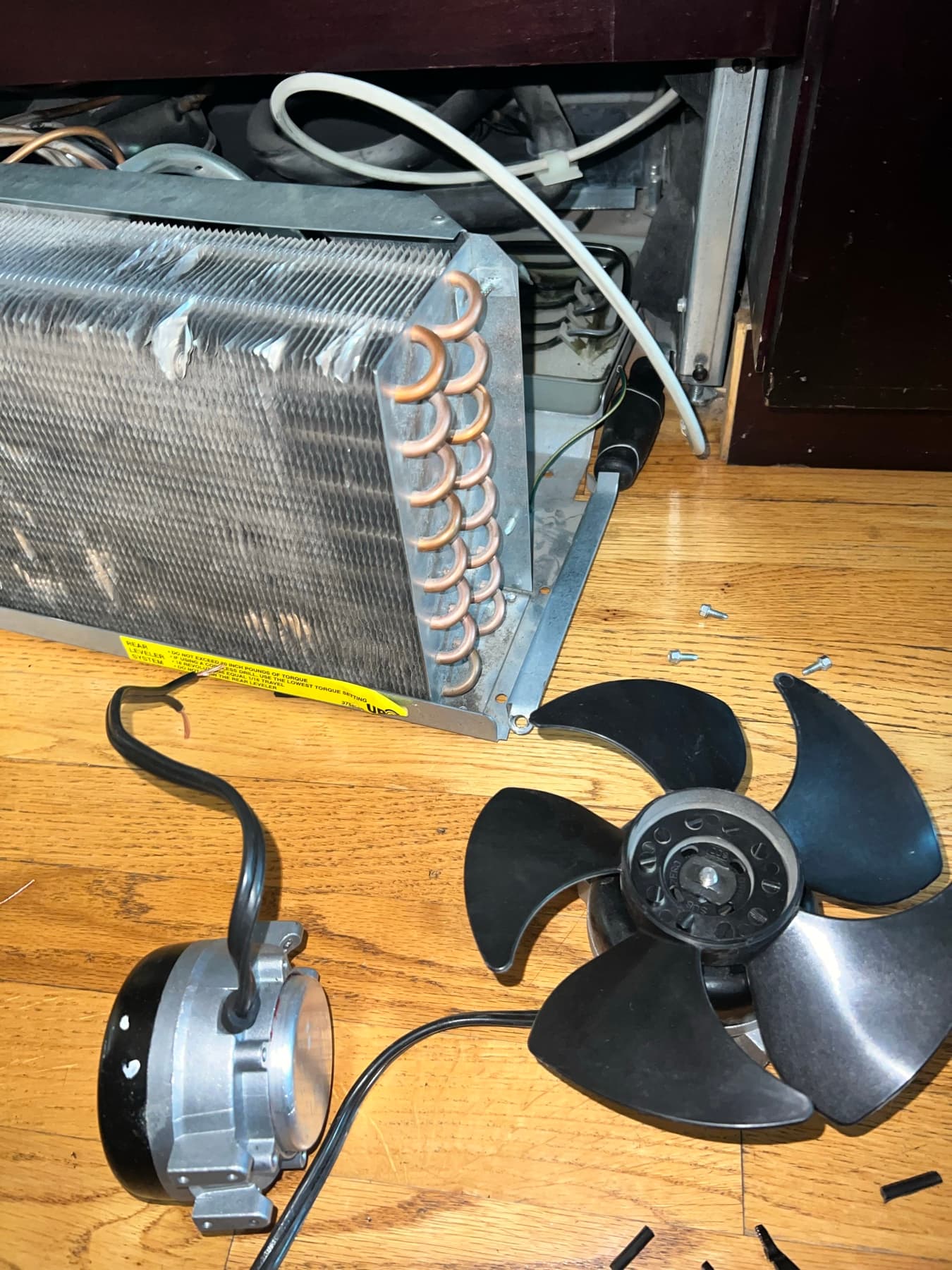 Refrigerator evaporator coil and condenser fan motor removed for repair